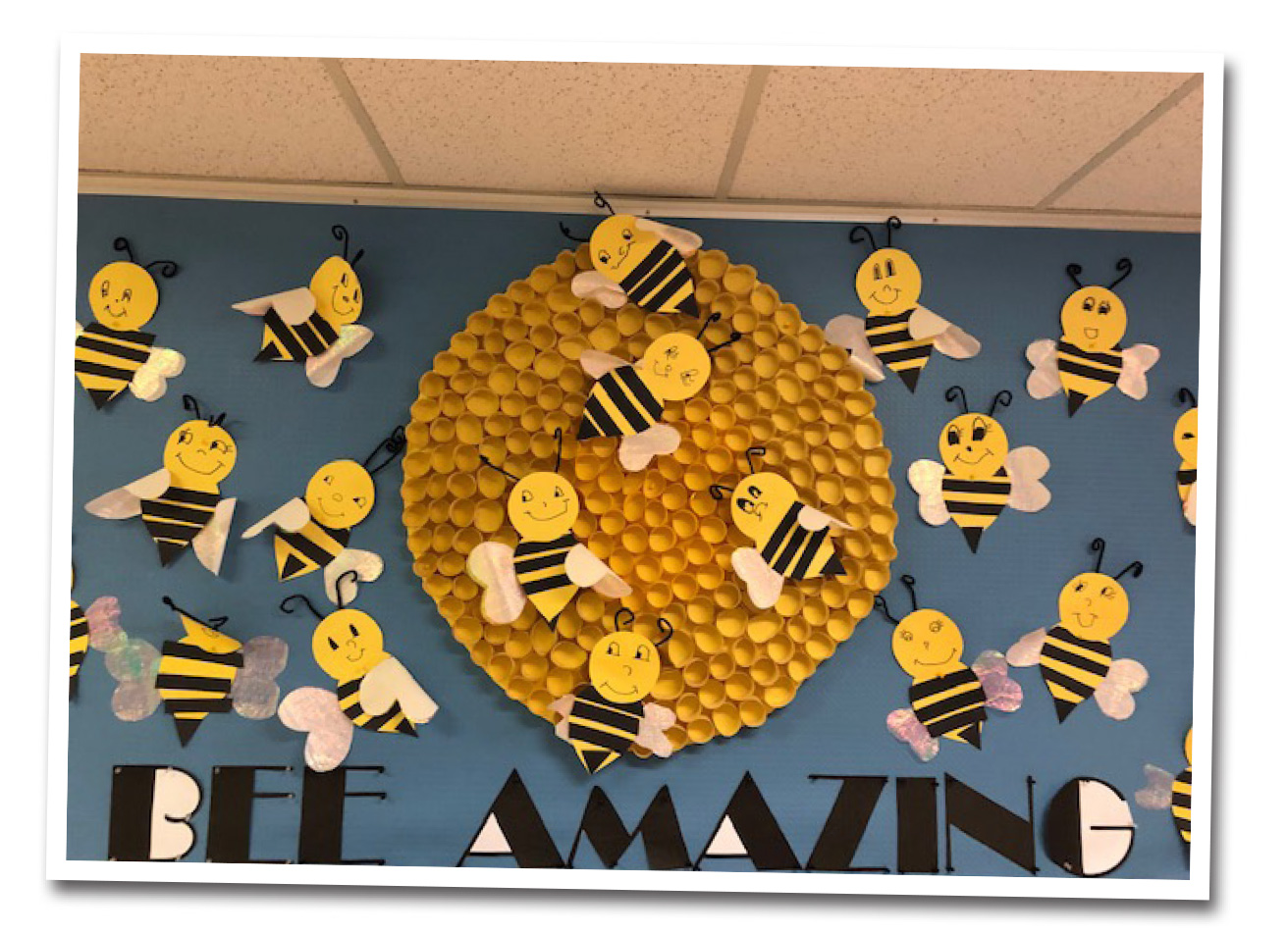 Craft wall art consisting of paper bees and the caption "Bee Amazing"