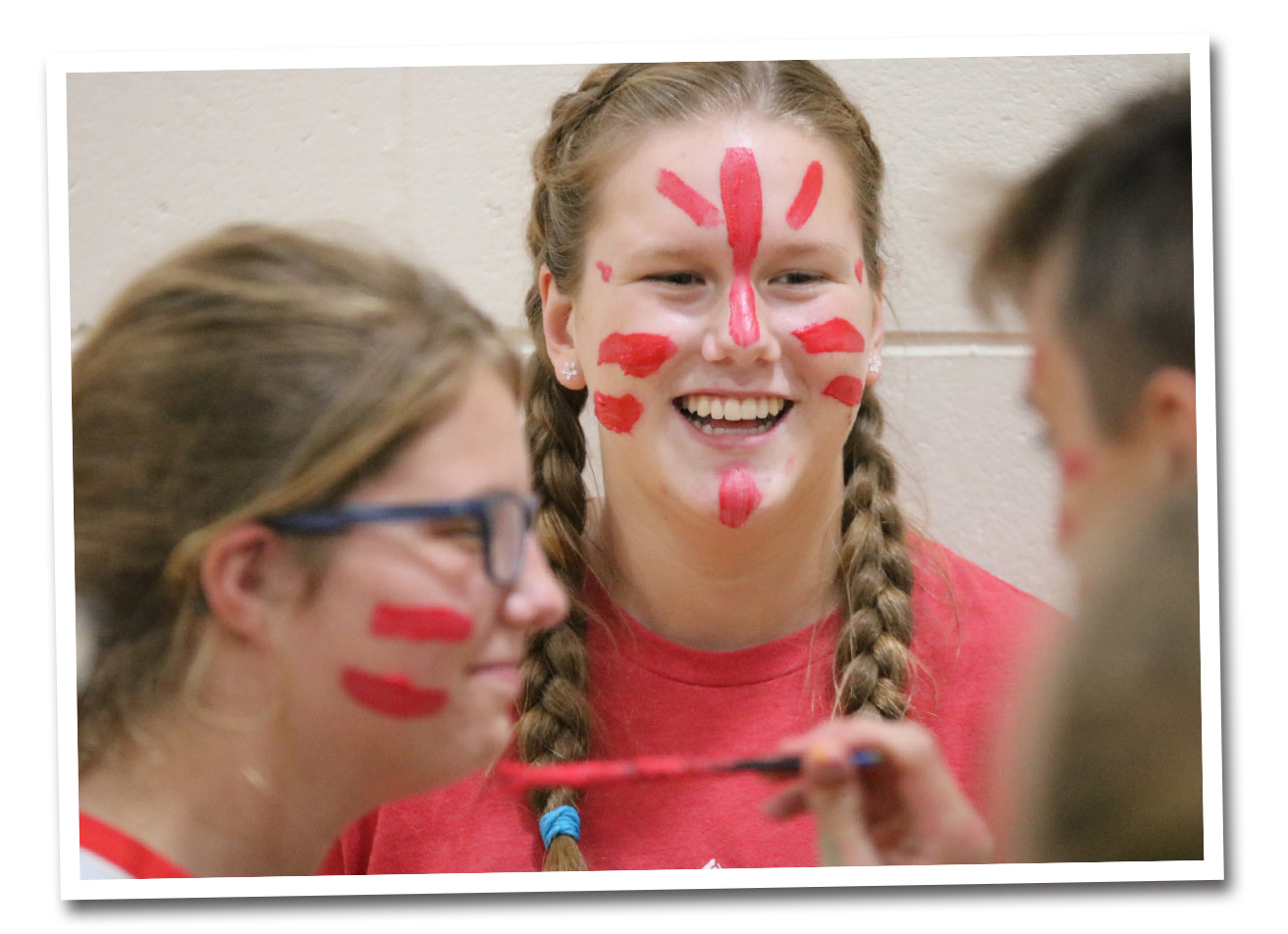 A female student watcher her friend get a similar face paint.