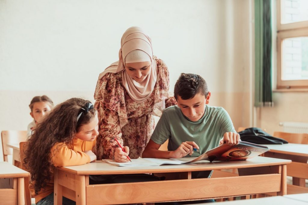 Teacher wearing hijab assisting students