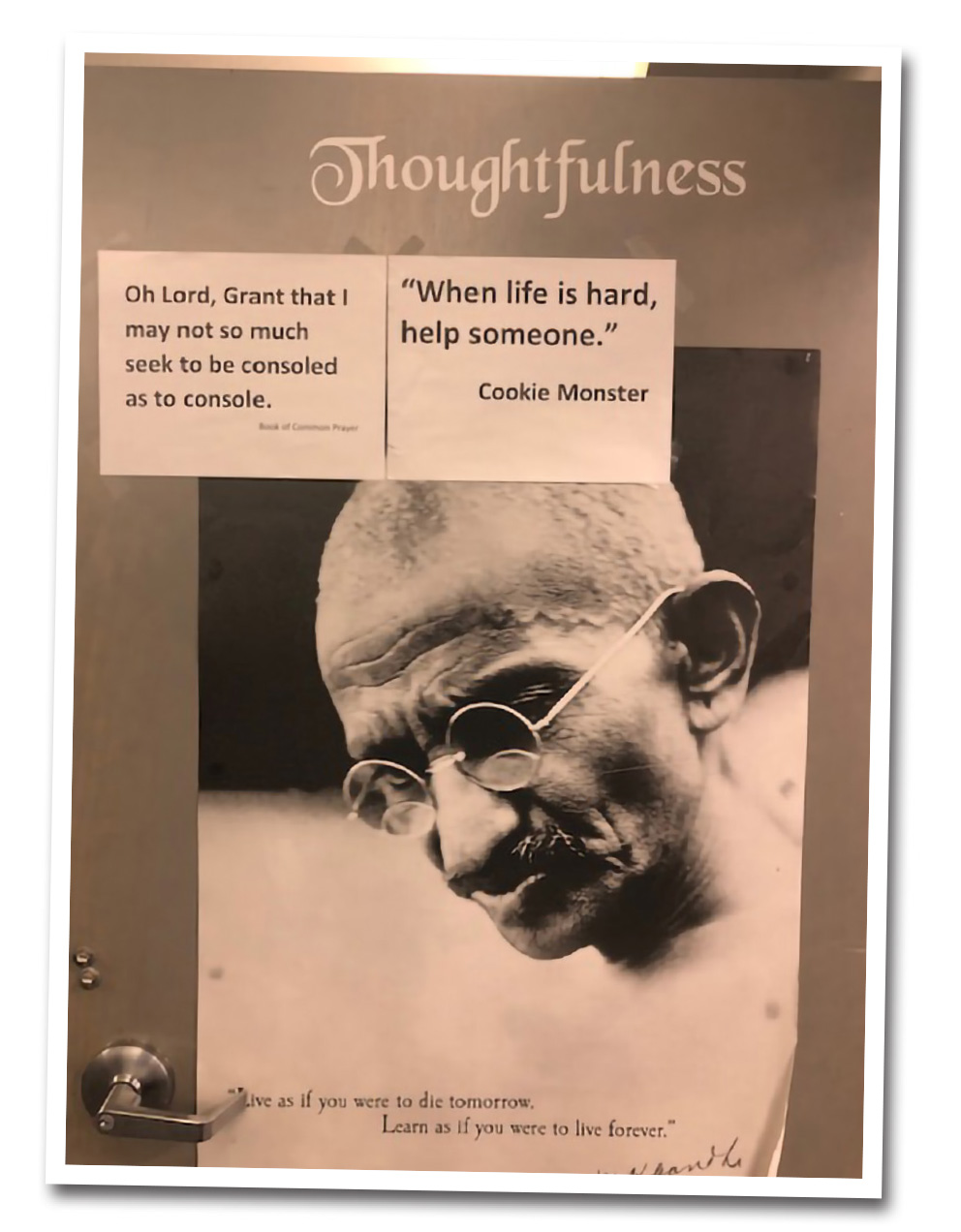 A poster of Ghandi with inspirational quotes taped to it.