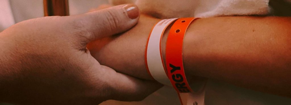 Mother holds hand of child in hospital.